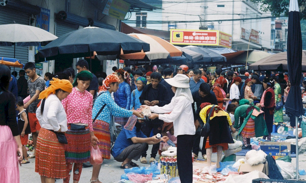 Vendors selling fresh vegetables and handmade goods at Meo Vac market